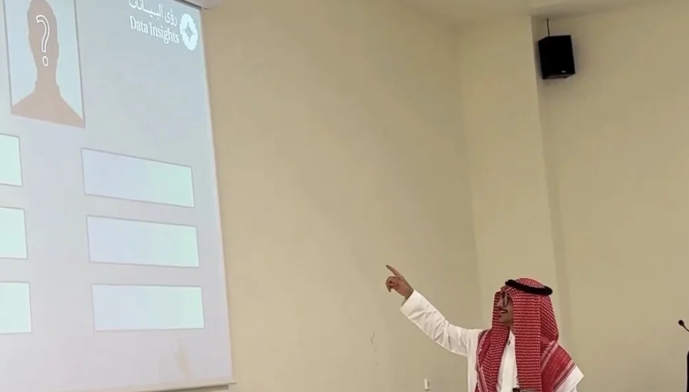 طارق يشير إلى لعبة تفاعلية معروضة على الشاشة في فعالية لمجتمع رؤى البيانات